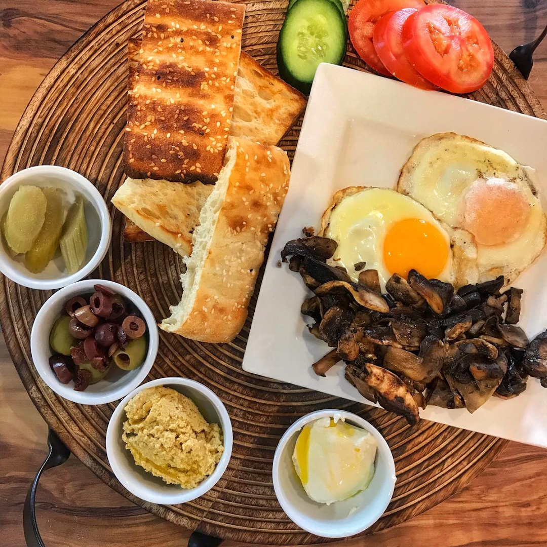 Breakfast spread with eggs, toast, mushrooms, olives, and condiments at La Grava